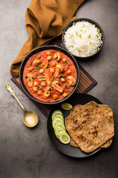 Mushroom sabzi in tomato curry with chickpea and spinach, Indian main course menu served with Paratha and cooked white rice