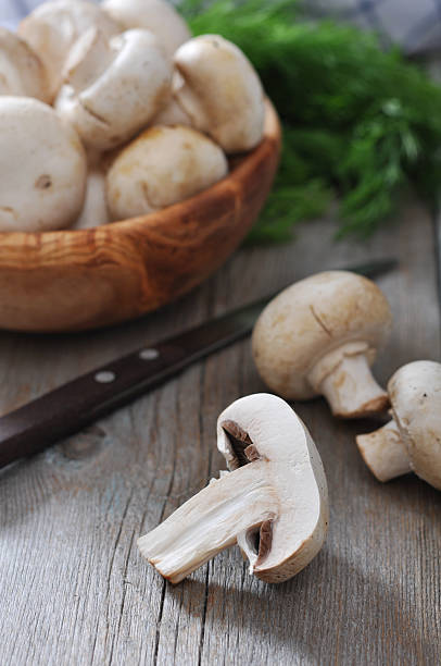 Fresh mushrooms champignon in bowl on wooden background